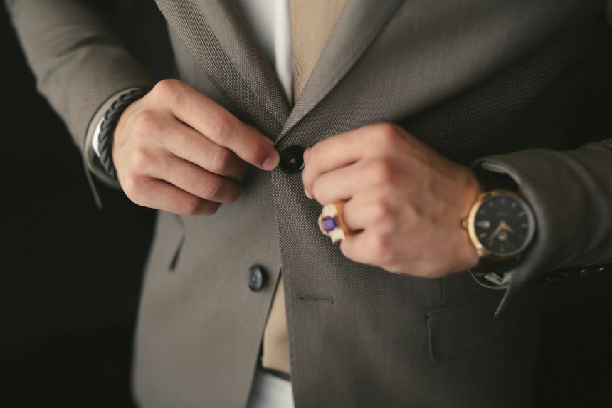 A man puts on a wedding suit and fastens a button