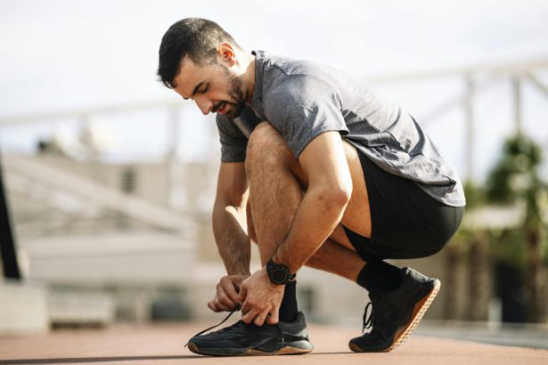 Sports man tying shoe laces in preparation for running training. Handsome young male getting ready