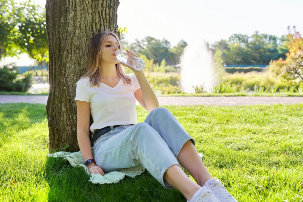 Young woman drinking water from a bottle on a hot summer day