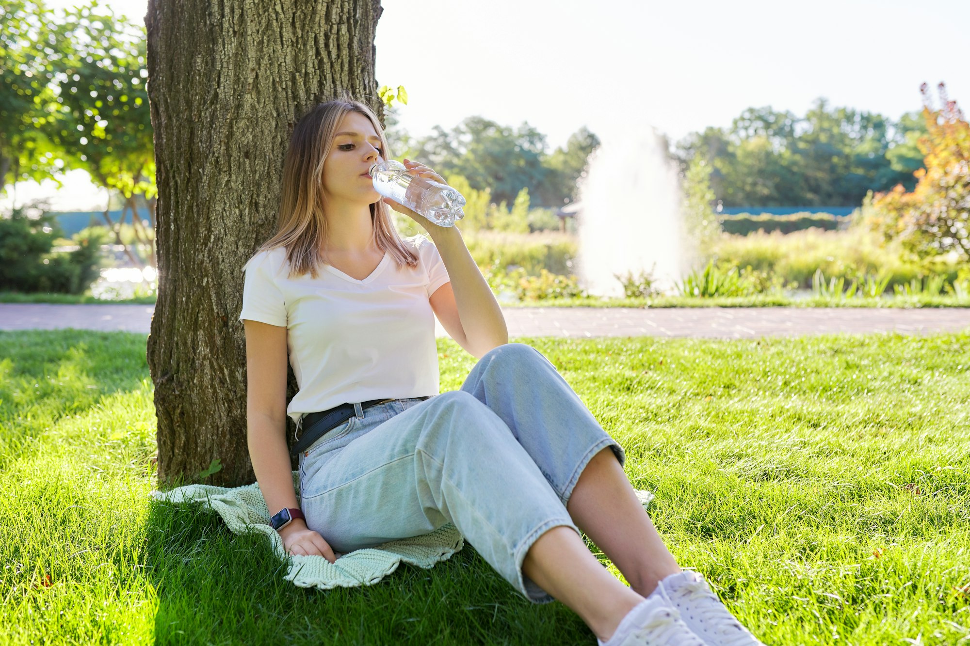 Young woman drinking water from a bottle on a hot summer day
